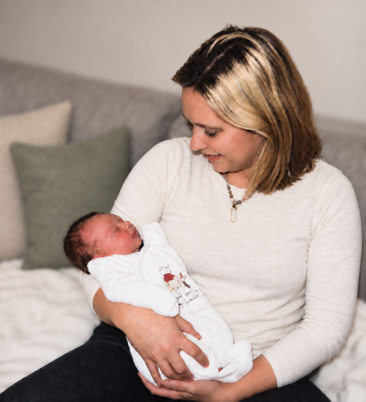 Kelly gently cradling a sleeping newborn